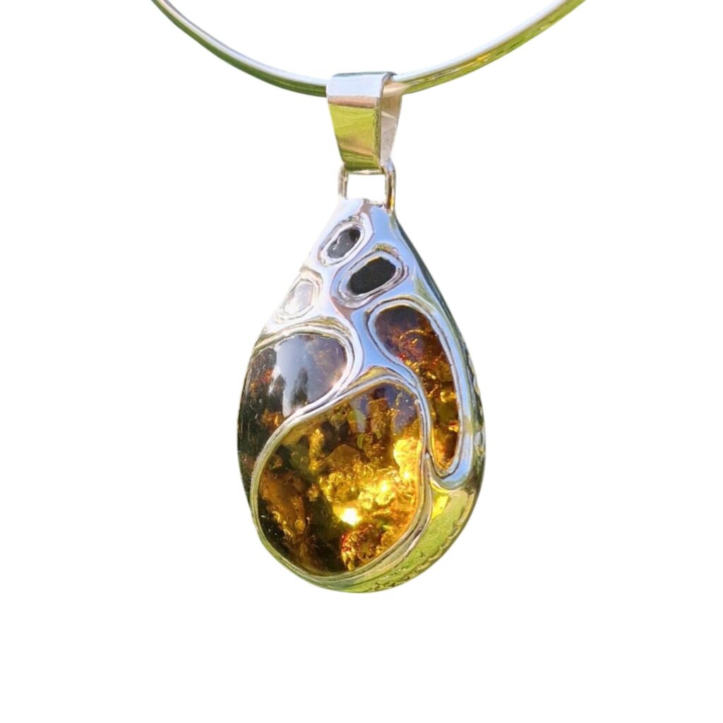 A LEGENDARY MASTERPIECE OF ARTISAN CRAFTSMANSHIP – A COLLECTOR’S DREAM: Teardrop-shaped pendant with an exquisite amber centerpiece, elegant silver design, and smooth loop for hanging.