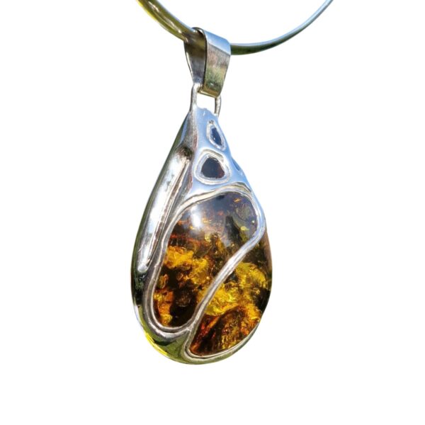 A legendary masterpiece of artisan craftsmanship, this teardrop-shaped amber pendant features silver accents and mesmerizing inclusions, making it a collector's dream.