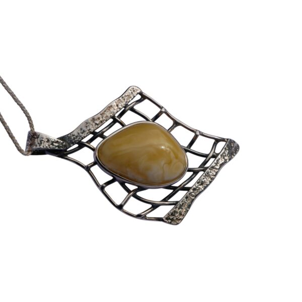 The "AMBER EMBRACE: BUTTERSCOTCH AMBER & SILVER NET PENDANT SET" features a silver pendant with an abstract grid design, highlighting a polished amber stone in the center.