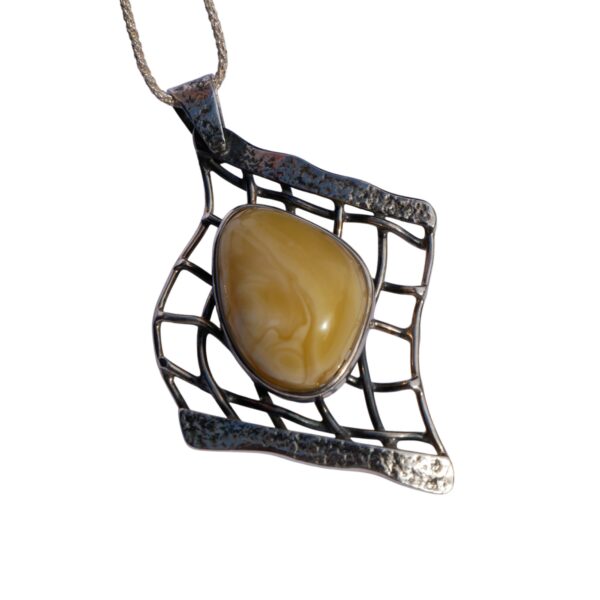 The AMBER EMBRACE set features a pendant with a striking silver net design, highlighting a butterscotch amber stone at its core, gracefully hanging from a silver chain.