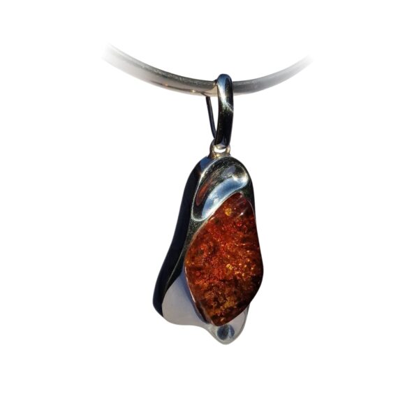 The CHUNKY COGNAC AMBER PENDANT IN SOLID SILVER is a polished, irregular-shaped silver necklace exuding timeless elegance.