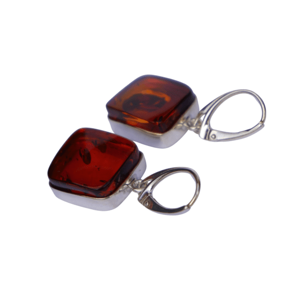 a pair of earrings with a red square