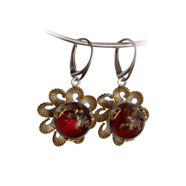 a pair of earrings with red and gold decorations