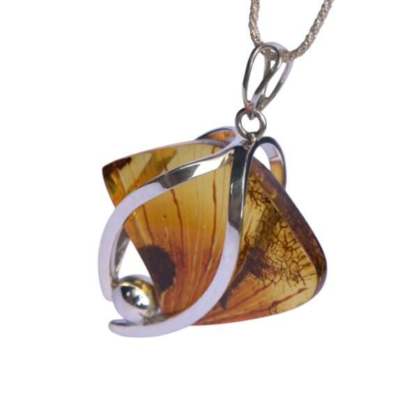 The NATURE'S SCULPTED AMBER is a silver pendant with a vibrant amber gemstone, highlighted by intricately curved metal accents, elegantly hanging from a chain.